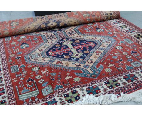 A vintage Caucasian carpet, light red and cream ground with three central medallions and stylised geometric designs, 303cm by