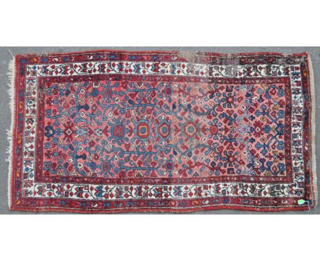 A vintage mid century Persian Islamic carpet floor rug. Red ground with floral repeating patterns, with white border and furt