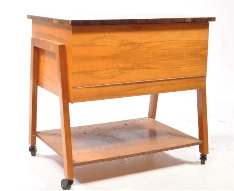British Modern Design - A vintage 20th century walnut sewing trolley. With hinged lid under tier with square supports termina