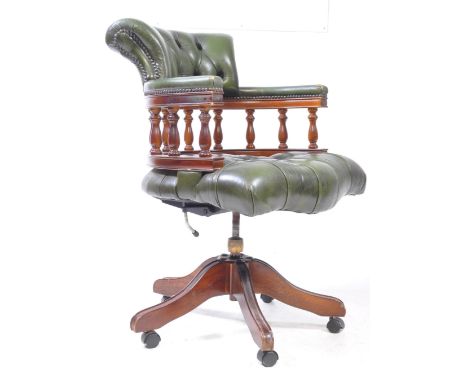 An early 20th century green leather button back captains desk chair / swivel armchair. The chair raised on a splayed base wit
