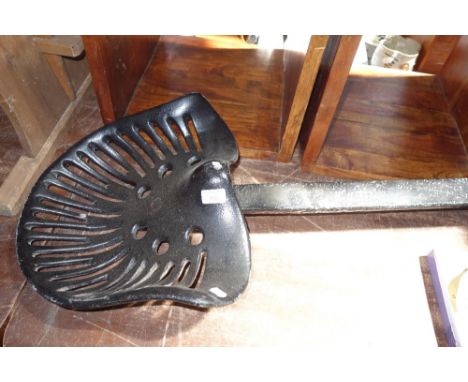 A VINTAGE CAST IRON TRACTOR SEAT stamped 'HXT' with supporting bracket