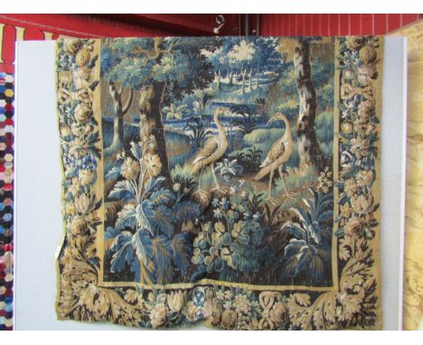 An handwoven wall hanging tapestry featuring a woodland scene with foliage and stylised birds flanked by a border of pomegran