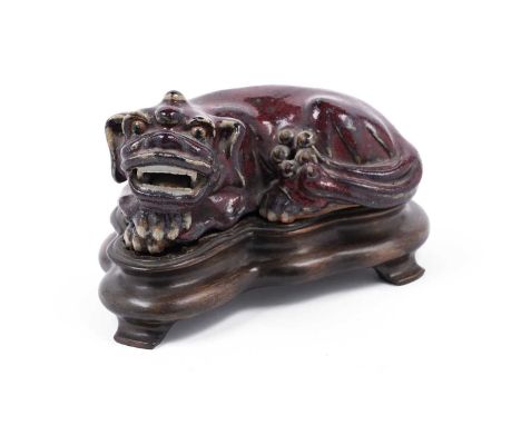 A 19th Century Chinese flambe glazed stoneware figure of a recumbent Buddhist lion, impressed seal mark, fitted hardwood stan