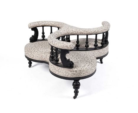 A Victorian ebonised and upholstered triple seat conversation chair, later upholstered in a cream and brown floral fabric, th