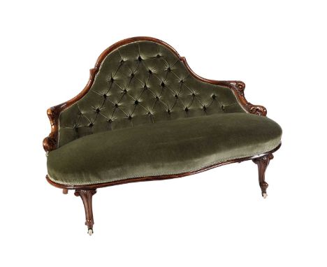 A Victorian carved walnut button back upholstered settee, upholstered in green plush material, the arched back with carved fo