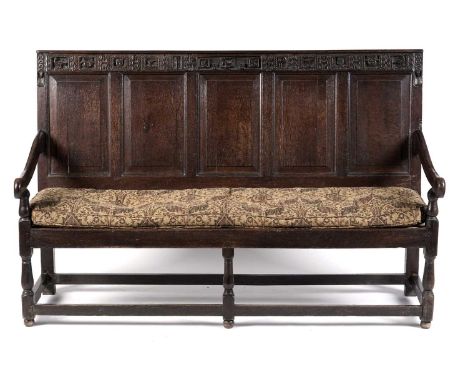 A 18th Century oak settle, the top rail heavily carved with animals and faces with the letters 'I' and 'P', dated 1656, over 