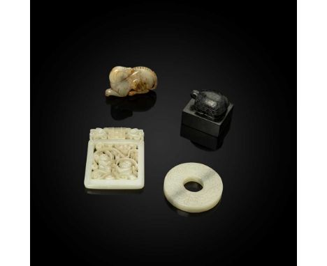 GROUP OF FOUR JADE PIECES  各式玉雕（共四件） comprising: a greyish white with russet skin jade carving of a recumbent dog; a black ja