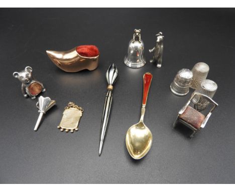 THREE SILVER THIMBLES, THREE NOVELTY PIN CUSHIONS AND A SILVER TOOTH FLASK, along with charms, trinkets and an enamelled spoo