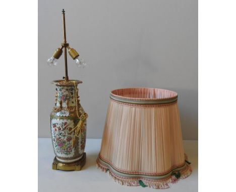A CHINESE CANTON FAMILLE ROSE VASE, converted to a table lamp, with shade, the panels profusely decorated with a corncucopia 