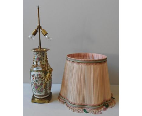 A CHINESE CANTON FAMILLE ROSE VASE, converted to a table lamp, with shade, the panels profusely decorated with a corncucopia 