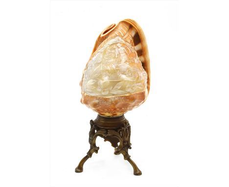 A carved conch shell lamp, the central scene carved with a female figure in classical dress riding in a chariot within a foli