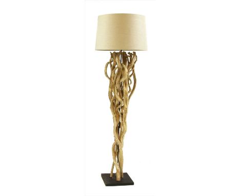 A driftwood standard lamp, made of wrythen branches on a black square base, with a calico shade, 176cm high