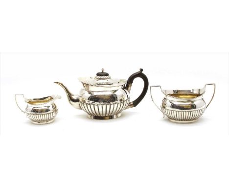 A late Victorian silver three piece tea service, comprising of teapot sucrier and cream jug, having half reeded ovoid body fi