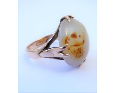 An oval cabochon agate ring to the trifucated shank stamped 9K  (The cost of UK postage via Royal Mail Special Delivery for t