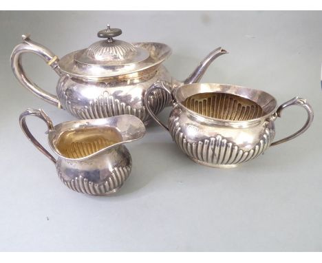 A hallmarked silver three-piece tea service comprising teapot, two-handled sugar and milk jug, each with lobed lower base, ma