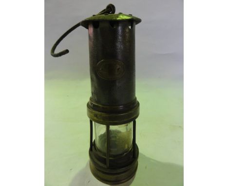 A 19th century miners lamp with brass mounts and cylindrical glass lens bearing plaque reading E. Thomas & Williams & Ltd, Ab