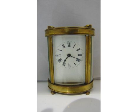 A brass carriage clock, the case of oval format enclosing an 8-day timepiece