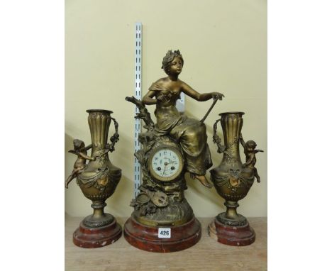 A Victorian spelter clock garniture, the clock case set within a rocky column surmounted by a lady with a tablet and pen and 