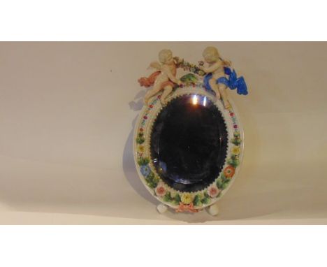 An early 20th century continental mirror frame with encrusted floral decoration and applied figures of cherubs holding a flor