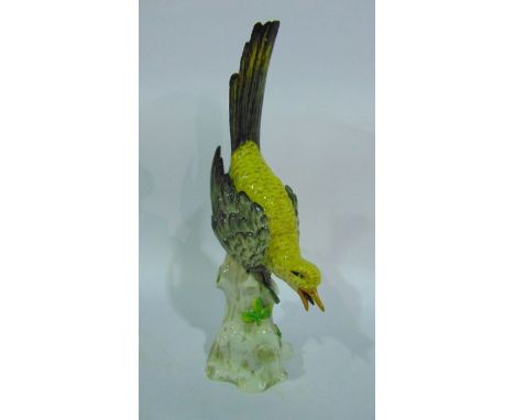 A 19th century continental model of a bird, probably by Sitzendorf, with yellow and grey plumage perched on a base in the for