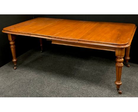 A Victorian mahogany extending dining table, the rounded rectangular top with moulded edge, turned and reeded legs, ceramic c