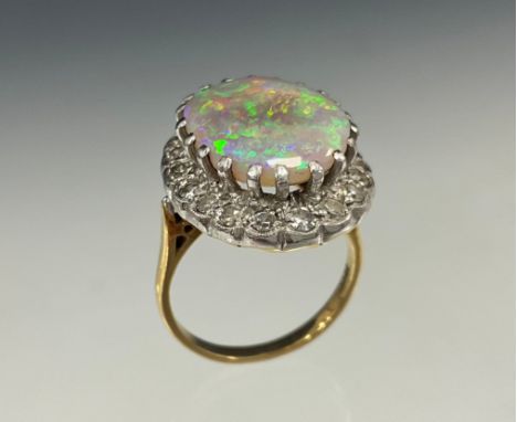 An impressive opal and diamond cluster ring, large oval opal cabochon approx 17mm x 13mm flashing vibrant violet blue, green 