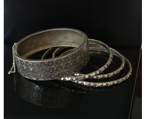 A silver stiff hinge bangle and three other ornate bangles