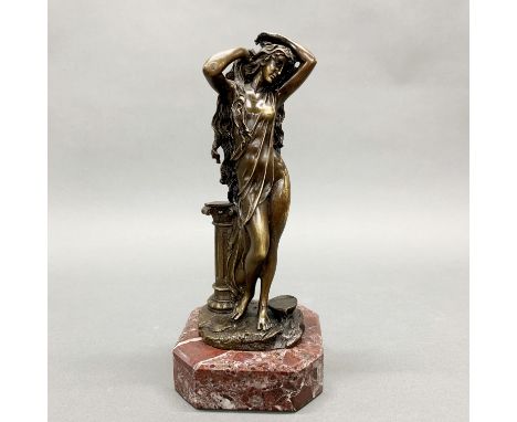 A bronze figure of a girl washing her hair on a red marble base, H. 30cm.