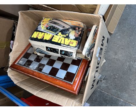 A misc box of games to include chessboard, GrandStand CaveMan, etc. 