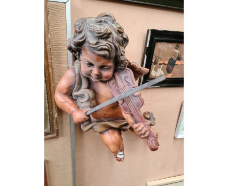 A vintage hanging figure of a cherub playing a violin. 