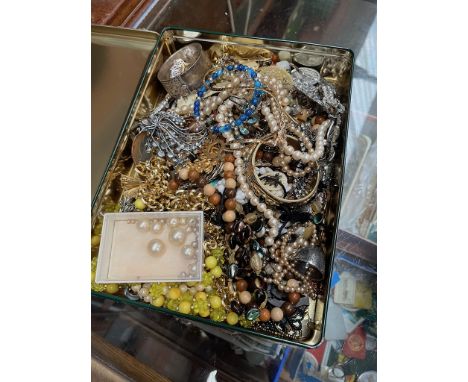 A tin of costume jewellery to include brooches, necklaces, simulated pearls, silver bangle, etc. 