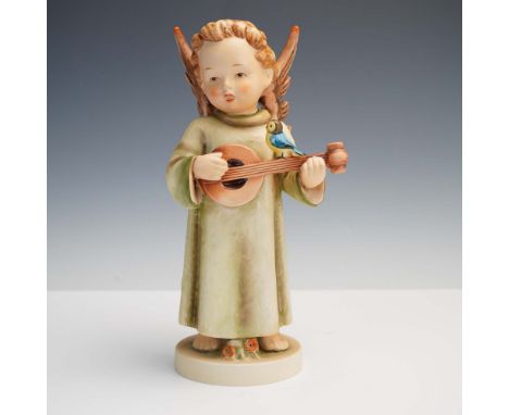 This Goebel Hummel porcelain figurine depicts a serene angel standing barefoot, gently strumming a mandolin adorned with a vi