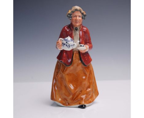 Porcelain figurine depicting an older woman in mid-gesture pouring tea. The figure wears a red jacket over a light blouse wit