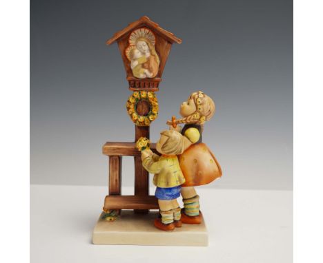 Charming Goebel Hummel porcelain figurine titled Adoration, featuring a young girl and boy placing a floral wreath beneath a 