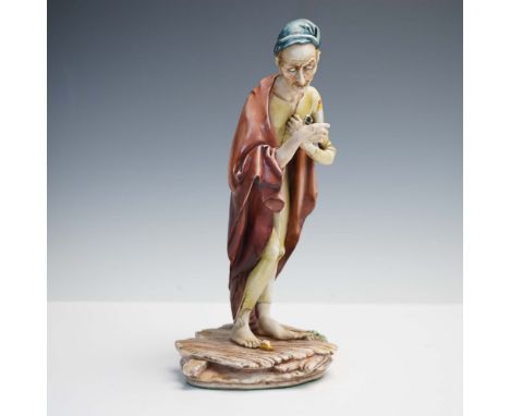Crafted by master Italian sculptor Antonio Borsato, this porcelain figurine depicts a gaunt, elderly man holding a candle clo