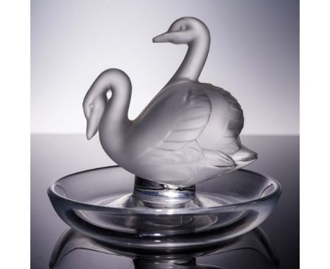 This delightful Lalique crystal ring dish features a pair of frosted swans elegantly poised back-to-back at the center of a c