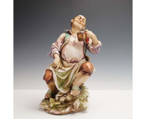 This finely sculpted porcelain figurine by Antonio Borsato depicts a jovial, bald man seated on a rocky base, joyfully raisin