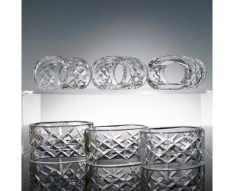 Set of six oval-cut glass napkin rings featuring cross-cut patterns and the etched Waterford mark. Two retain original foil l