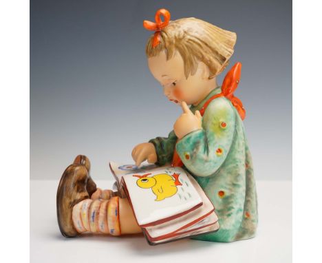 This charming Goebel Hummel porcelain figurine titled Bookworm (HUM 117) features a young girl intently studying a brightly i