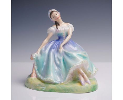 The figurine depicts a ballerina seated gracefully on a bench, with her head gently tilted and her arms resting along the ben
