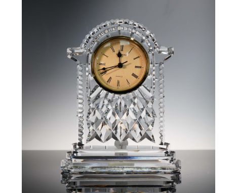 This Waterford Crystal carriage clock features a striking arched silhouette with diamond-cut detailing, topped by a classic r