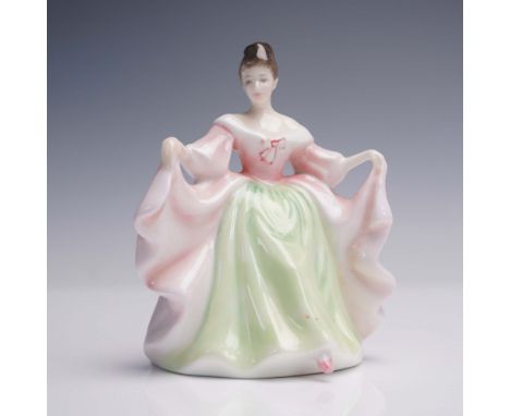 Bone china miniature figure portrays a woman in a formal gown holding up both sides of her skirt. The dress features a soft p