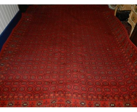 A Persian Bokhara style carpet, having geometric pattern on a red ground. L.325cm W.235cm