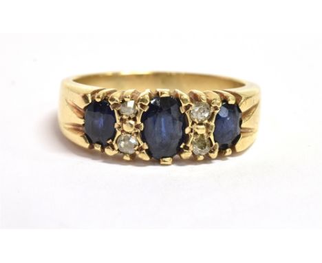 A SAPPHIRE AND OLD CUT DIAMOND DRESS RING the ring set with three faceted oval cut inky blue sapphires of graduated sizes, th