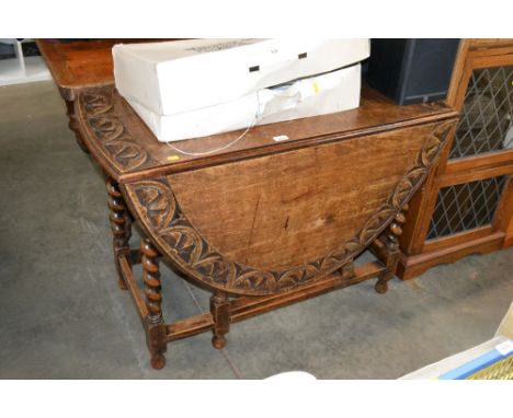 A carved oak gate leg table raised on barley twist supports