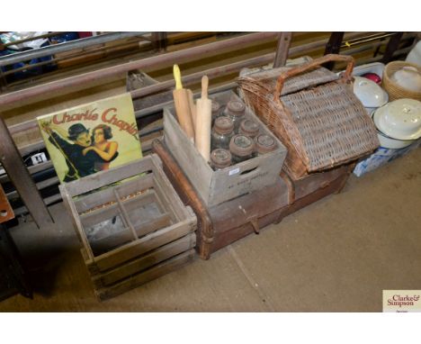 A wooden bound travelling trunk; a wicker basket; two wooden crates; a collection of storage jars; rolling pins and a Charlie