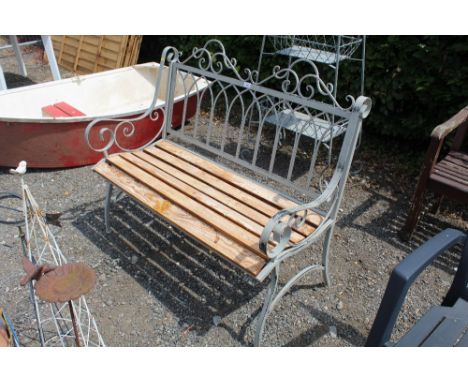 An ornate wooden and metal slatted two seater garden bench