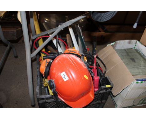 A box containing a still safety helmet and ear defender set, various garden tools and jump cables etc