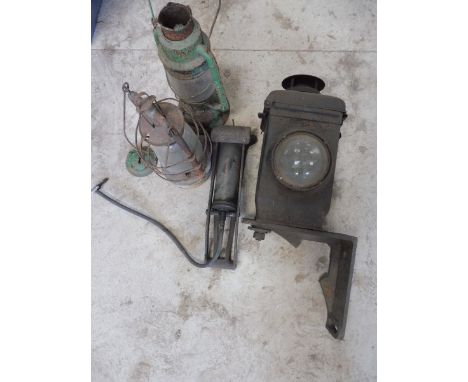 A railway lamp, two others and a foot pump. 