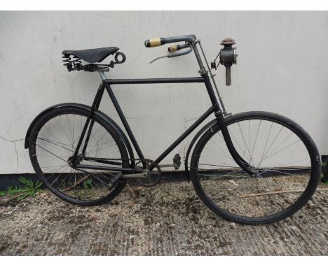 A gent's bicycle with early braking mechanism on the front tyre, with brass bell and paraffin lamp.